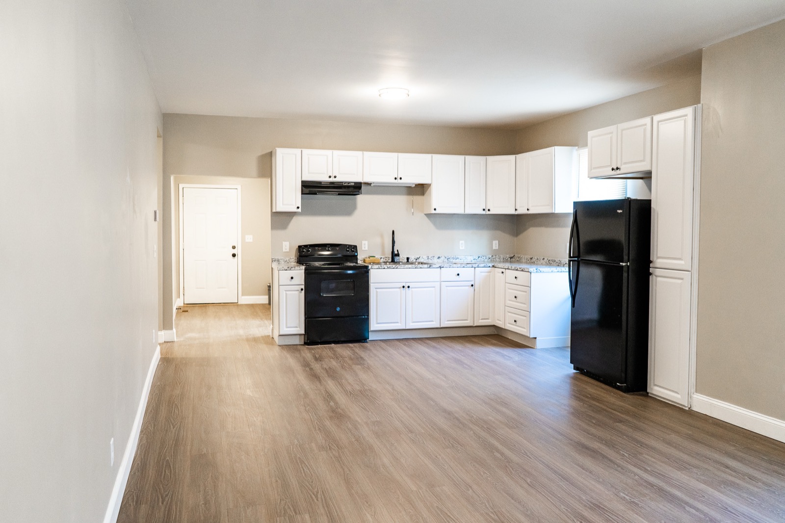 Renovated kitchen with white cabinets and wood-look floors